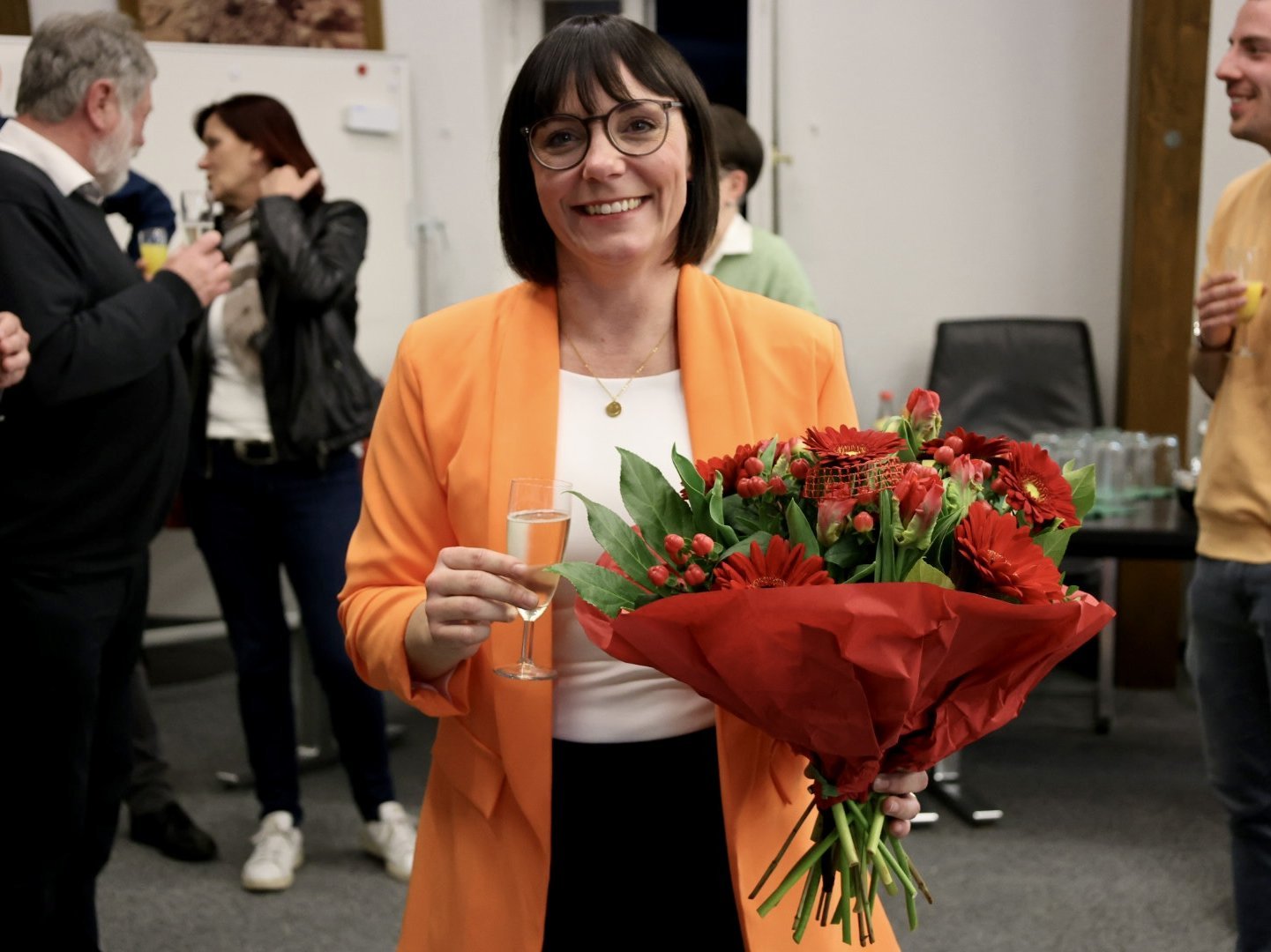 Sarah Höfler mit Blumenstrauß und Sektglas im Sitzungssaal